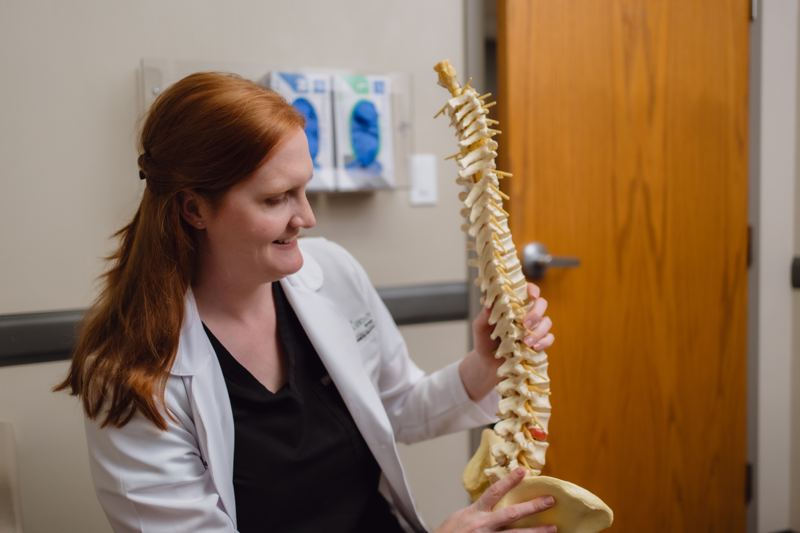 Dr. McShane smiling while holding a model of the human spine